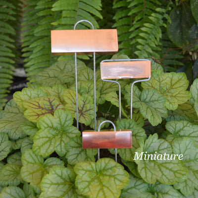 Miniature copper plant labels standing in a row