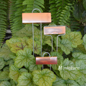 Miniature copper plant labels standing in a row